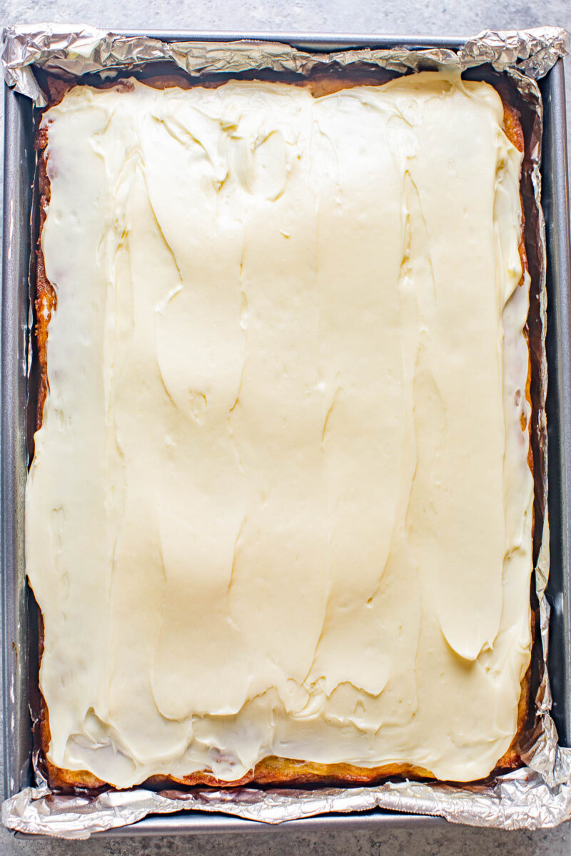 Best Banana Cake with Cream Cheese Frosting in a foil-lined baking pan.