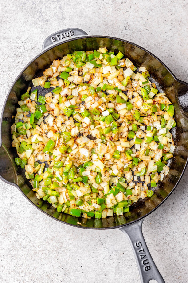 Sautéed onions and peppers in a cast-iron skillet.