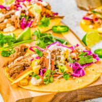 Pulled Pork Tacos - The BEST pulled pork tacos made with slow cooker pulled pork, nestled in tortillas, and then topped in abundance with Cilantro Lime Slaw, Pickled Red Onions, and Avocado Crema! Learn how to make these Mexican-inspired classic recipes at home! Easy enough for weeknights but also great for events, game day parties, get-togethers like Cinco de Mayo fiestas or graduation parties!