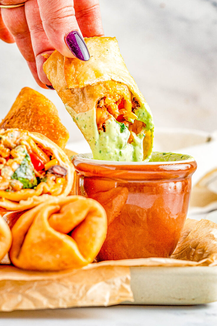 Southwestern Egg Rolls - Juicy chicken, melted Pepper Jack cheese, black beans, bell peppers, and corn seasoned with southwest-inspired seasonings and fried to crispy PERFECTION! You can fry, air fry, or bake these EASY egg rolls which are a Chili's Restaurant copycat. The quick creamy mashed avocado ranch dipping sauce is the perfect final touch!
