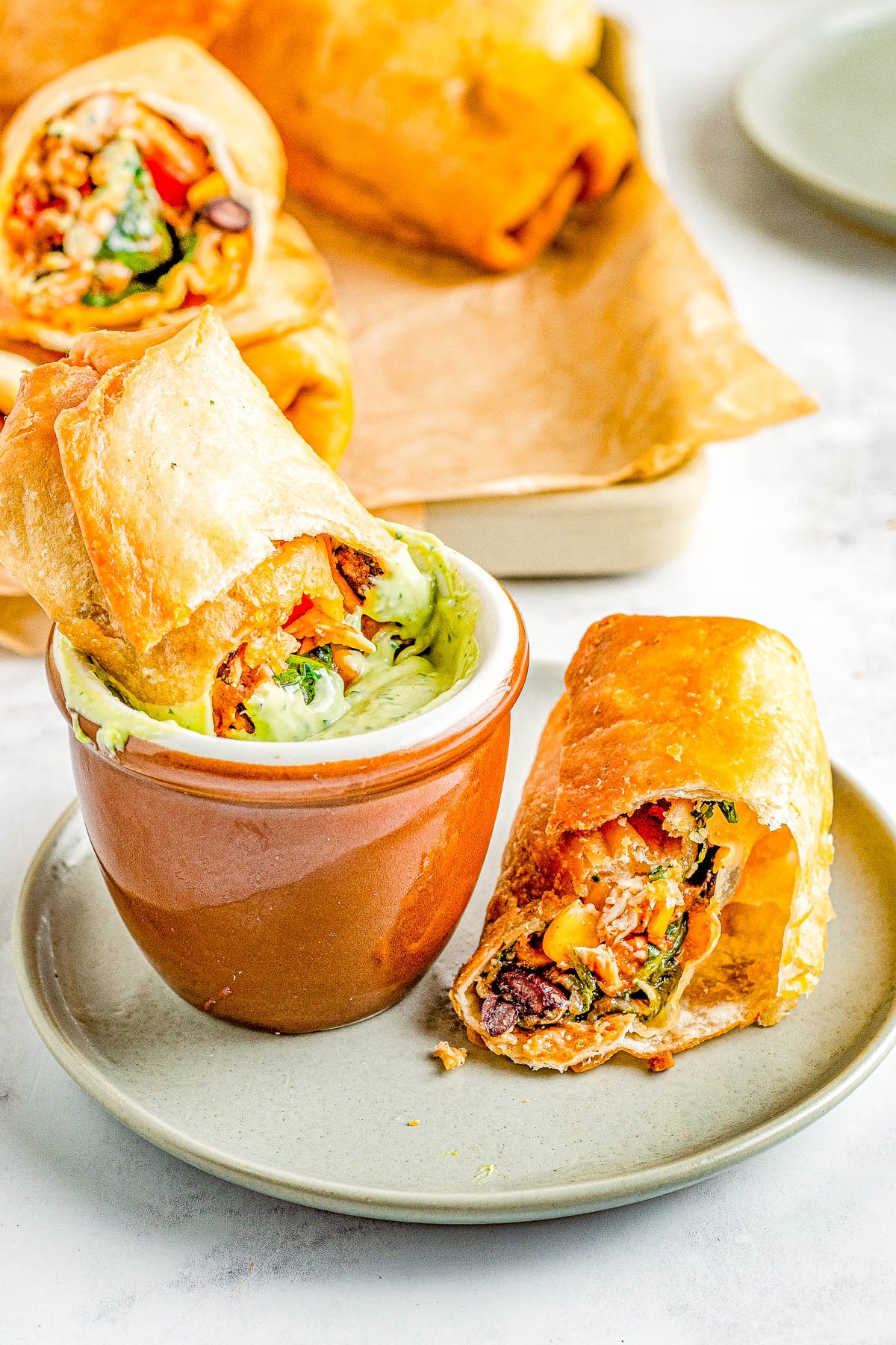 Southwestern Egg Rolls - Juicy chicken, melted Pepper Jack cheese, black beans, bell peppers, and corn seasoned with southwest-inspired seasonings and fried to crispy PERFECTION! You can fry, air fry, or bake these EASY egg rolls which are a Chili's Restaurant copycat. The quick creamy mashed avocado ranch dipping sauce is the perfect final touch! 