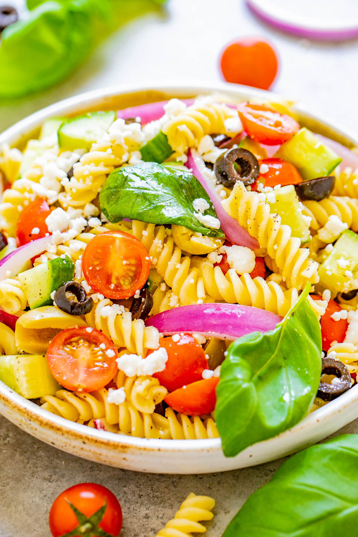 Mediterranean Pasta Salad - Juicy tomatoes and cucumbers, black and green olives, crumbled feta, and tender pasta are tossed in a homemade balsamic vinaigrette! An EASY pasta salad recipe with Mediterranean-inspired ingredients that's ready in under 30 minutes! It makes a big batch and is perfect for potlucks, picnics, or planned leftovers.