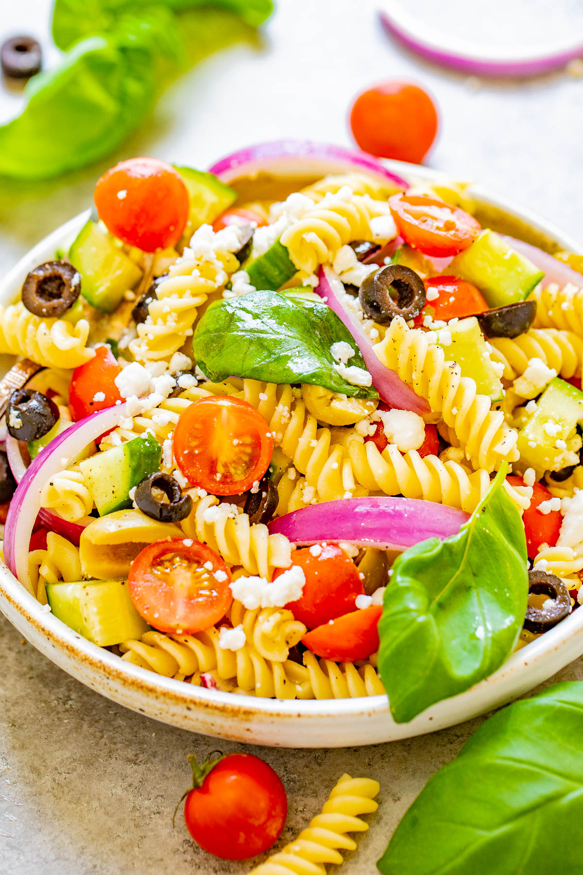Mediterranean Pasta Salad - Juicy tomatoes and cucumbers, black and green olives, crumbled feta, and tender pasta are tossed in a homemade balsamic vinaigrette! An EASY pasta salad recipe with Mediterranean-inspired ingredients that's ready in under 30 minutes! It makes a big batch and is perfect for potlucks, picnics, or planned leftovers. 