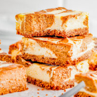 Pumpkin Cheesecake Bars — Classic cheesecake bars get an autumnal makeover in this recipe! A spiced pumpkin mixture is swirled into creamy cheesecake batter before being baked. Sweet, pumpkin spiced, CREAMY bars with a graham cracker crust for fabulous texture! PERFECT for fall gatherings or Thanksgiving! 