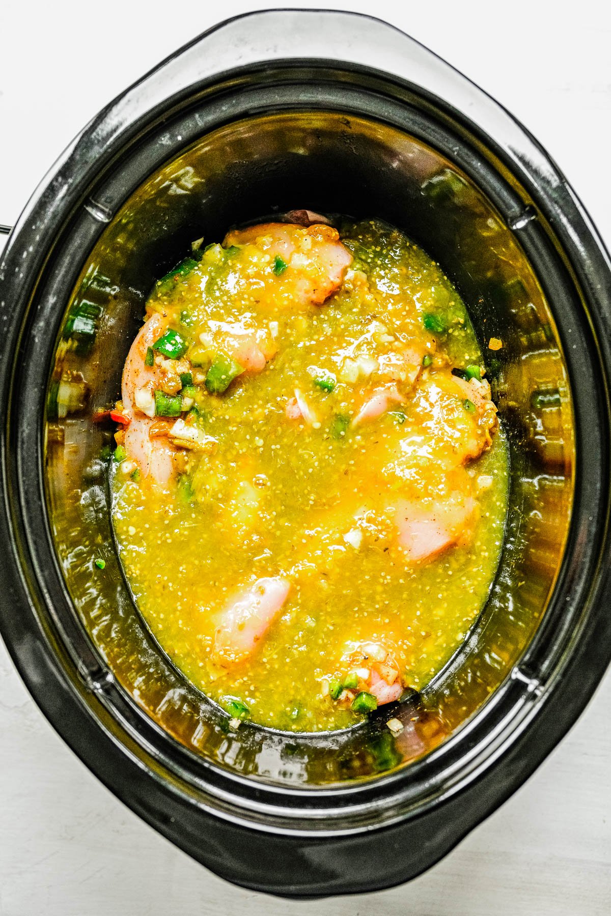 Slow Cooker Green Chile Chicken - Tender, juicy, chicken that's simmered with green chiles, jalapeno, salsa verde, onions, garlic, and spices for the most FLAVORFUL and versatile green chile chicken! Use it in tacos, burritos, casseroles, sandwiches, or as a meal prep recipe. Best of all, it's SO EASY because your slow cooker does ALL the work!