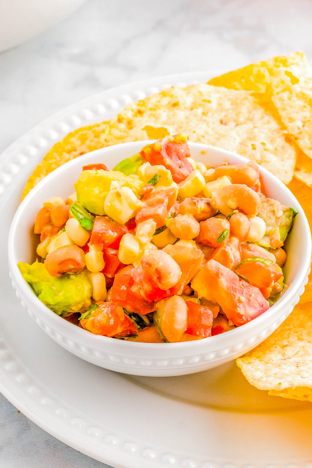 Texas Caviar - You don't need to buy this FAST and EASY crave-worthy appetizer or snack recipe made with Tex-Mex inspired ingredients including black eyed peas, tomatoes, corn, avocado, and a seasoned lime-cumin dressing! Serve it as a dip with tortilla chips at your next backyard barbecue, picnic, game day party, or for a holiday party. It's good luck to eat black eyed peas in the new year!