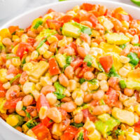 Texas Caviar - You don't need to buy this FAST and EASY crave-worthy appetizer or snack recipe made with Tex-Mex inspired ingredients including black eyed peas, tomatoes, corn, avocado, and a seasoned lime-cumin dressing! Serve it as a dip with tortilla chips at your next backyard barbecue, picnic, game day party, or for a holiday party. It's good luck to eat black eyed peas in the new year!