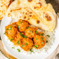 A plate of white rice, butter chicken meatballs, and naan.