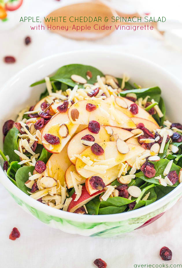 spinach cranberry salad topped with grated cheddar in a white bowl 