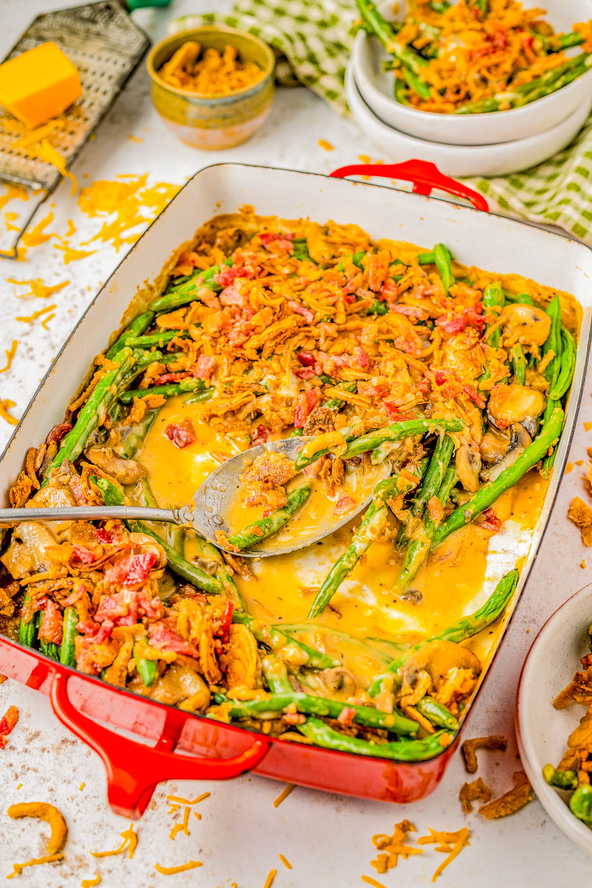 Smothered Bacon Green Bean Casserole — Homemade green bean casserole is made even better with the addition of BACON and CHEESE! Fresh green beans are smothered in a savory mushroom sauce before being topped with cheese, crumbled bacon, and fried onions. A truly decadent, cheesy casserole that’s perfect for Thanksgiving, Christmas, or when you're craving a comfort food side dish - and no canned or condensed soups in sight!
