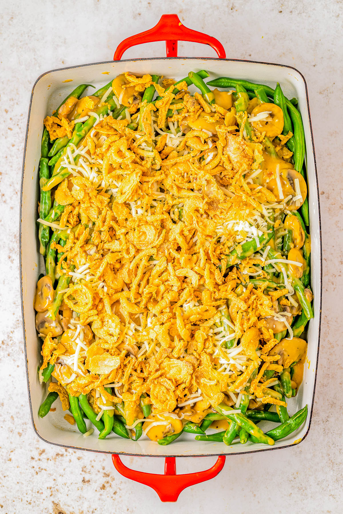 Smothered Bacon Green Bean Casserole — Homemade green bean casserole is made even better with the addition of BACON and CHEESE! Fresh green beans are smothered in a savory mushroom sauce before being topped with cheese, crumbled bacon, and fried onions. A truly decadent, cheesy casserole that’s perfect for Thanksgiving, Christmas, or when you're craving a comfort food side dish - and no canned or condensed soups in sight!