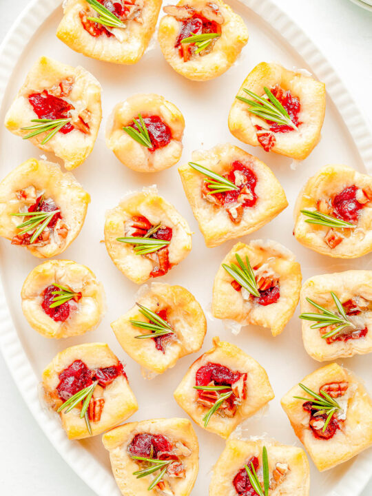 Cranberry Brie Bites - The perfect two-bite holiday appetizer recipe with melted brie cheese, sweet-tart cranberry sauce, and fresh rosemary all nestled inside a buttery soft crust! An EASY appetizer recipe with just 4 main ingredients that's ready in 30 minutes! PERFECT for Thanksgiving celebrations, holiday and Christmas parties, or for New Year's Eve!