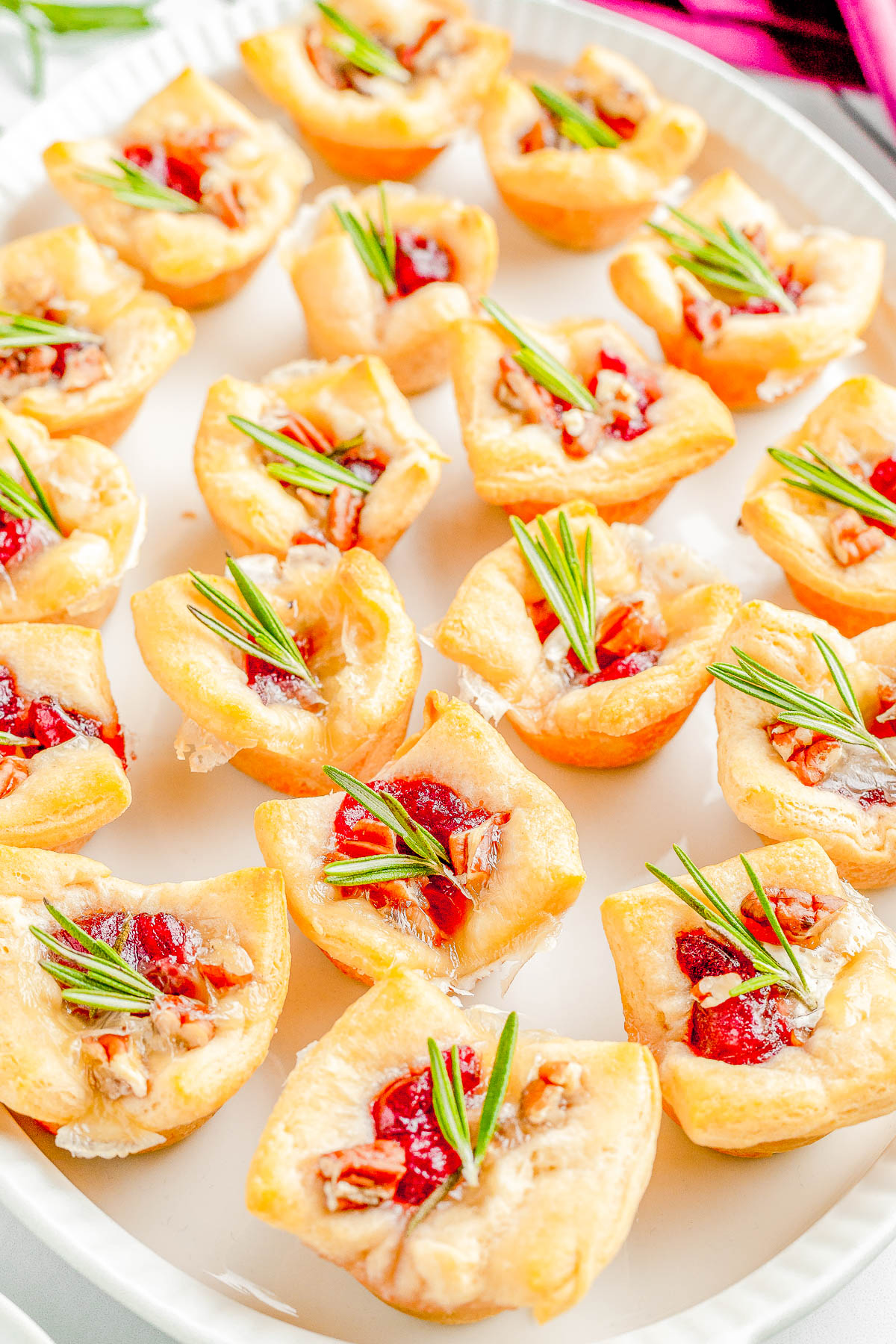 Cranberry Brie Bites - The perfect two-bite holiday appetizer recipe with melted brie cheese, sweet-tart cranberry sauce, and fresh rosemary all nestled inside a buttery soft crust! An EASY appetizer recipe with just 4 main ingredients that's ready in 30 minutes! PERFECT for Thanksgiving celebrations, holiday and Christmas parties, or for New Year's Eve! 