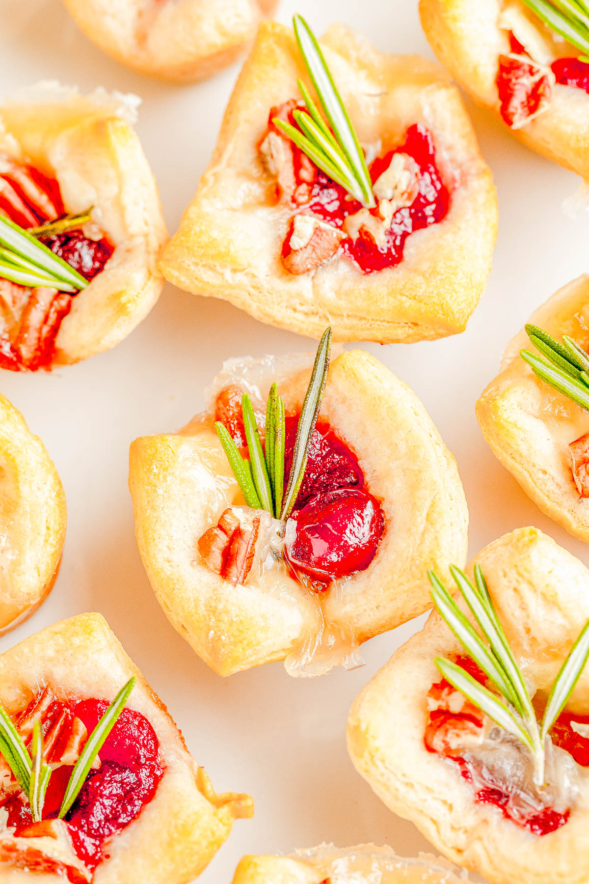 Cranberry Brie Bites - The perfect two-bite holiday appetizer recipe with melted brie cheese, sweet-tart cranberry sauce, and fresh rosemary all nestled inside a buttery soft crust! An EASY appetizer recipe with just 4 main ingredients that's ready in 30 minutes! PERFECT for Thanksgiving celebrations, holiday and Christmas parties, or for New Year's Eve! 