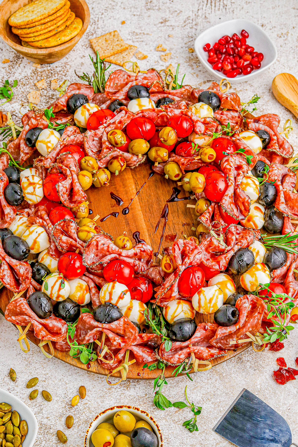 Holiday Antipasto Wreath - A fun and festive Christmas or New Year's Eve appetizer recipe idea that's so FAST and EASY to make! Skewered salami, mozzarella, tomatoes, olives, fresh herbs, and more come together to form the wreath. Mix-and-match the ingredients based on your favorites. You can prep it ahead of your party or event and when your guests see this, I guarantee everyone's eyes will light up! 