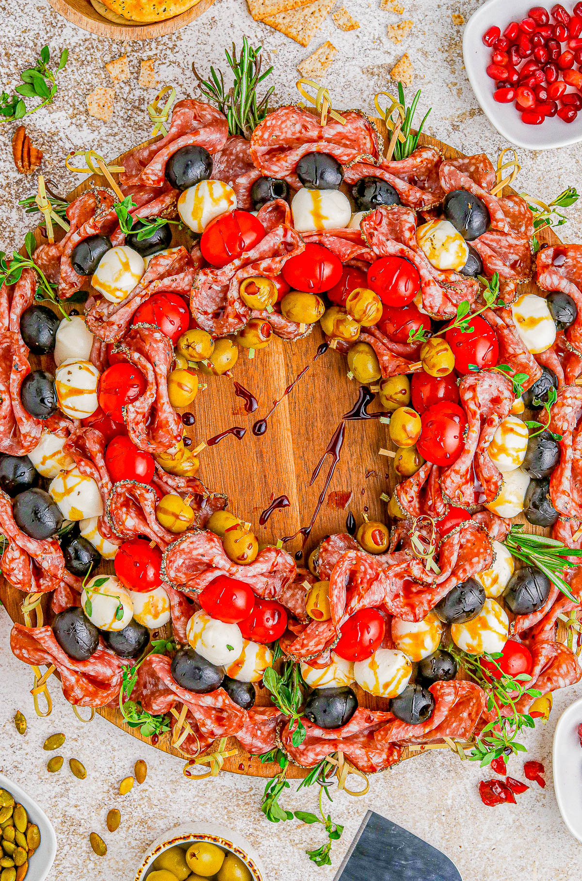 Holiday Antipasto Wreath - A fun and festive Christmas or New Year's Eve appetizer recipe idea that's so FAST and EASY to make! Skewered salami, mozzarella, tomatoes, olives, fresh herbs, and more come together to form the wreath. Mix-and-match the ingredients based on your favorites. You can prep it ahead of your party or event and when your guests see this, I guarantee everyone's eyes will light up! 