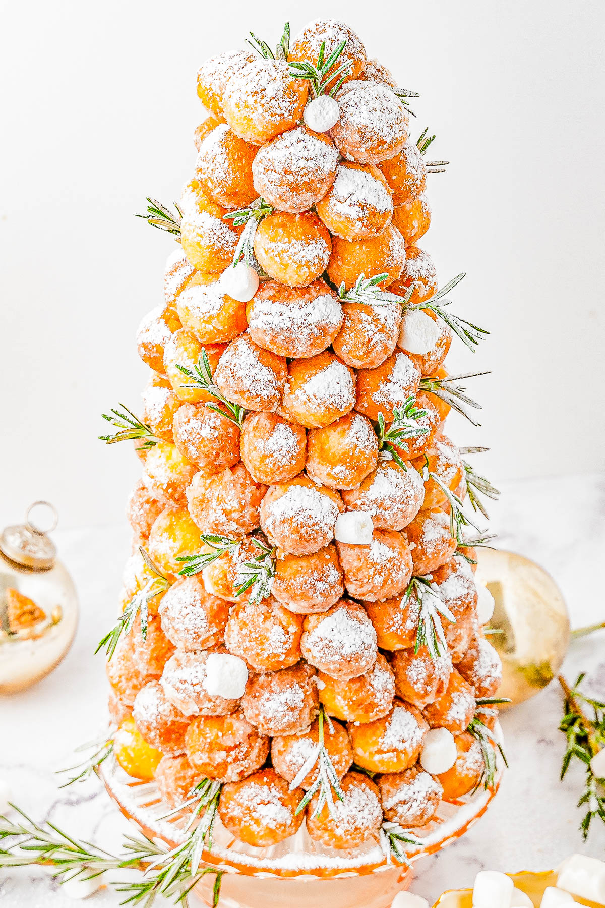Donut Hole Christmas Tree — Looking for a QUICK and EASY, yet FESTIVE centerpiece for your holiday dessert table or brunch spread? Try making a Christmas tree out of donut holes! All you need is a styrofoam cone from the craft store and some store-bought donut holes. Decorate your tree however you want, then let guests help themselves! 