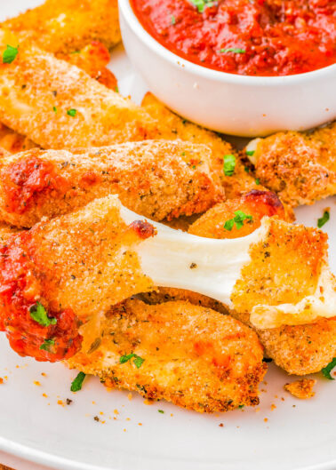 Air Fryer Mozzarella Sticks with Marinara Dipping Sauce - Soft, gooey, melted mozzarella cheese inside a crispy and lightly crunchy golden brown exterior is what you have with this quick and EASY mozzarella cheese sticks recipe! Pair them with my herb-flavored marinara sauce for dipping! The perfect appetizer for your next game day party, casual entertaining event, or just a tv night at home because everyone LOVES these! 