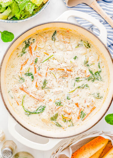 A pot of chicken gnocchi soup with spinach.
