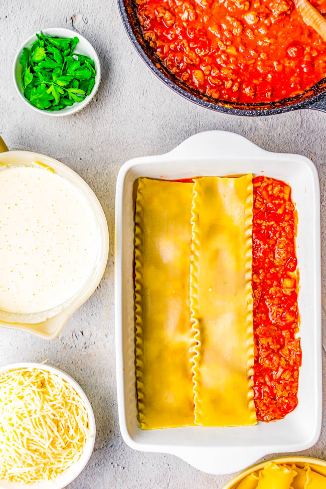 Preparation of lasagna with layers of pasta, sauce, and cheese ready to be baked.