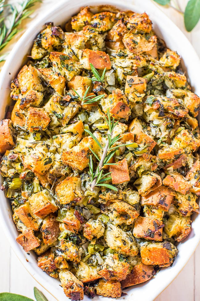 A dish of herbed bread stuffing garnished with a sprig of fresh rosemary.