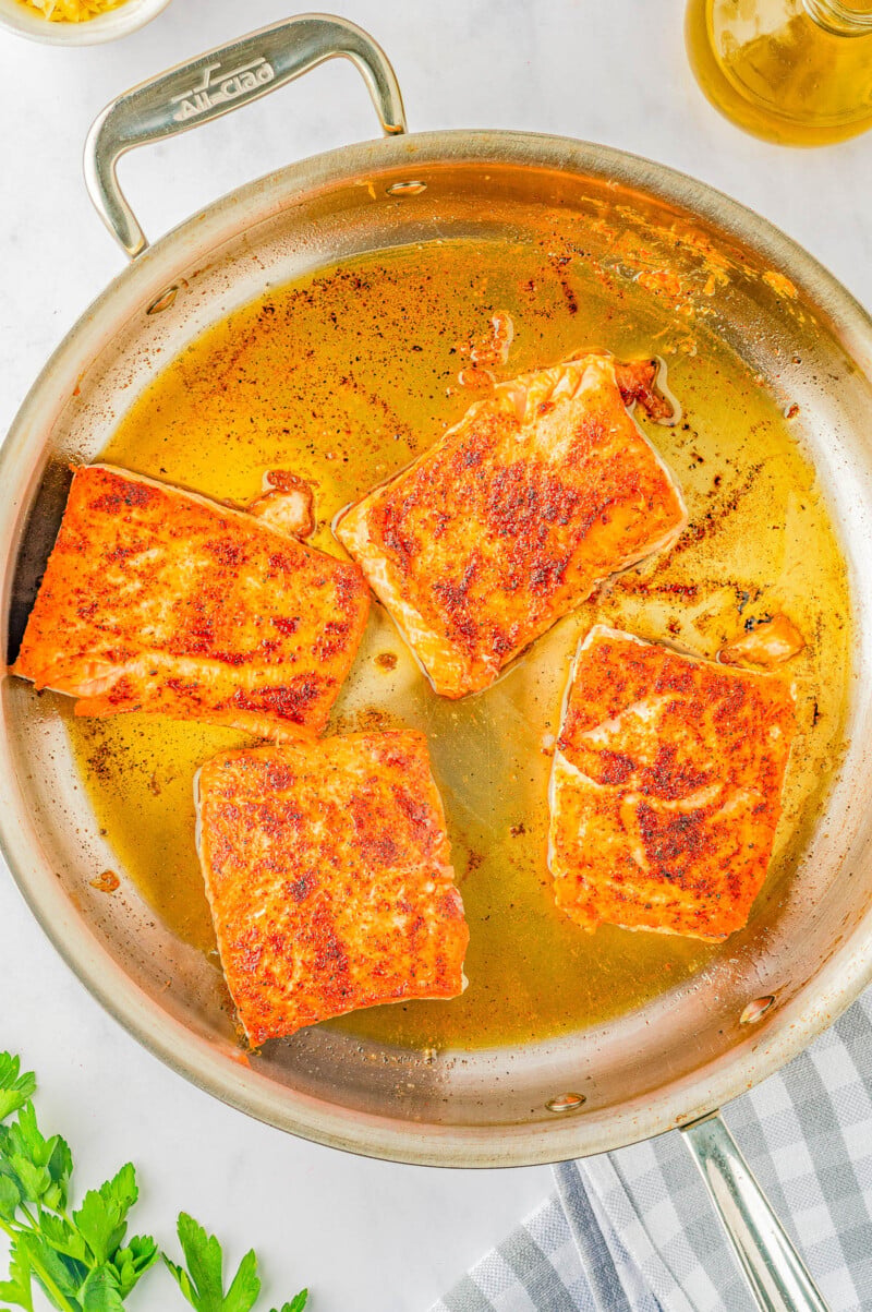Creamy Garlic Butter Tuscan Salmon - An EASY one-skillet salmon recipe for the most tender and juicy salmon that's bathed in a rich and creamy garlic butter sauce! Parmesan cheese, sun dried tomatoes, and baby spinach add extra flavor and texture to this 30-minute recipe that everyone LOVES! Learn how to make restaurant-worthy salmon that's fast enough for a weeknight dinner but elevated enough to serve to company!
