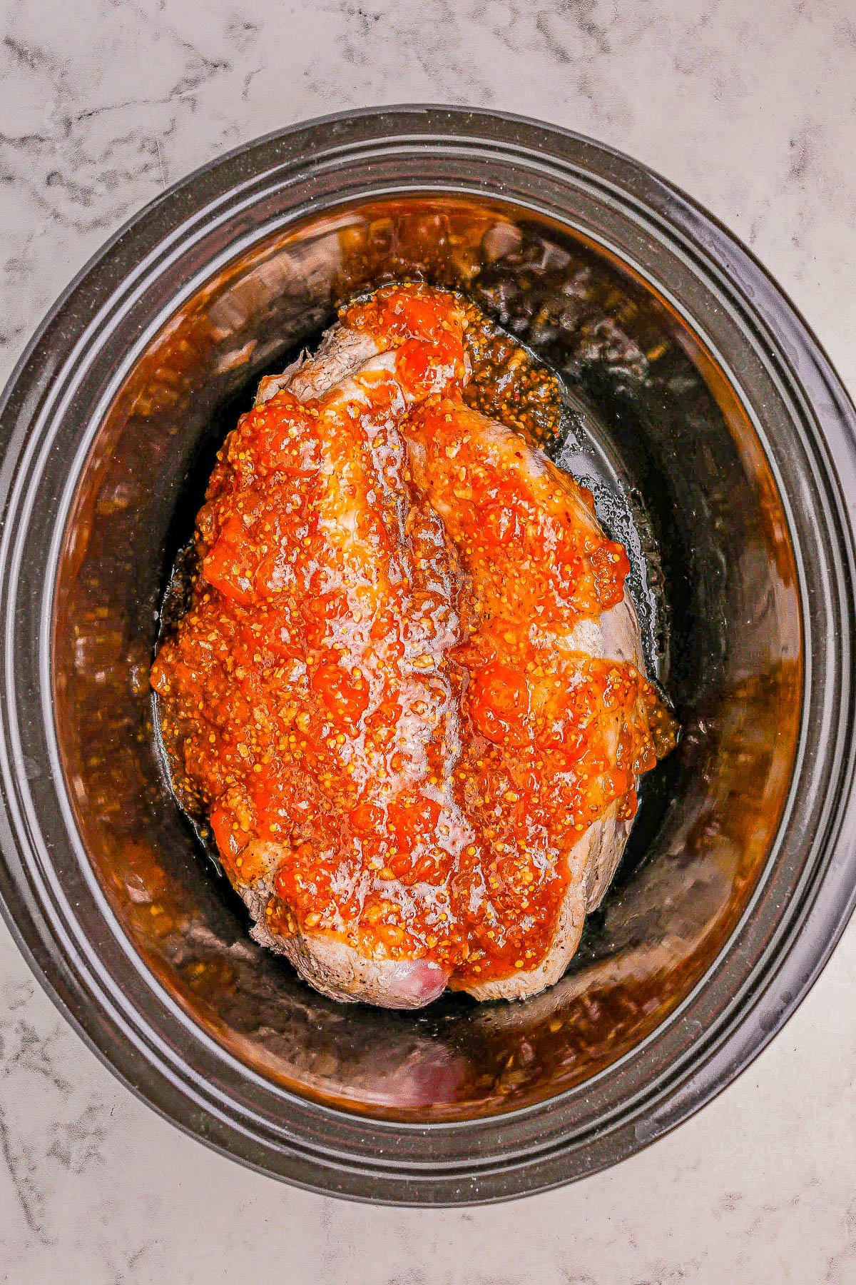 A seasoned pork roast in a slow cooker.