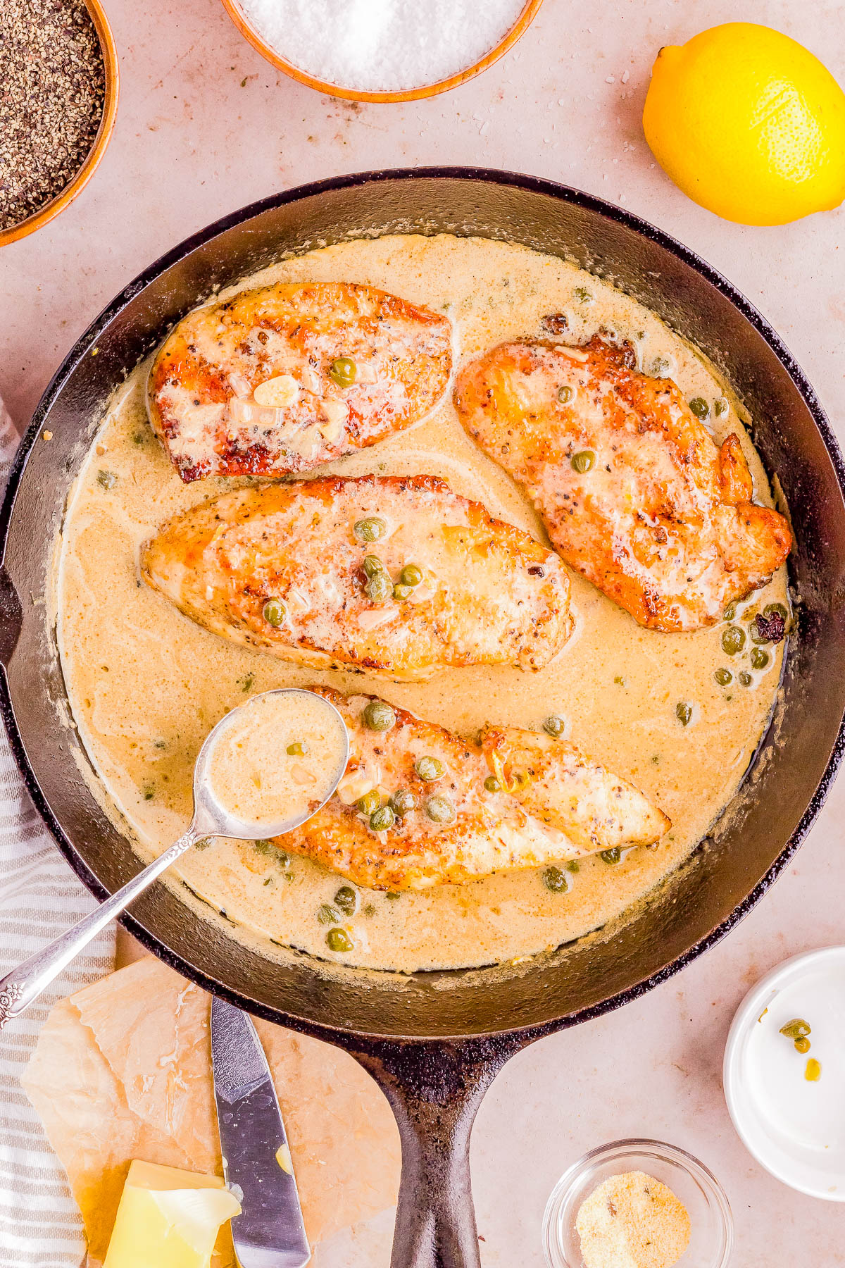 Pan-seared chicken breasts in a creamy sauce with capers, served in a cast iron skillet.