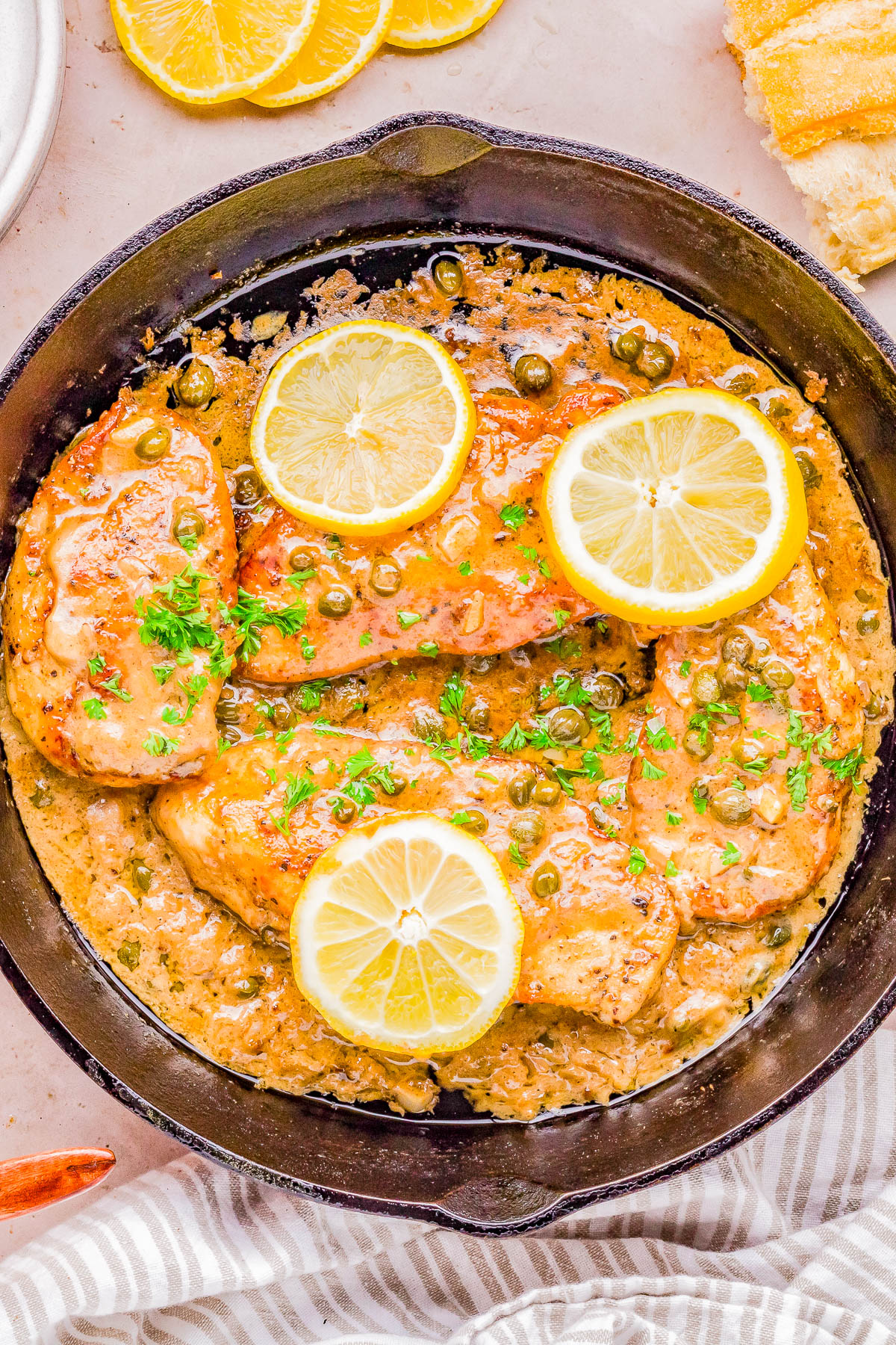 Chicken piccata with lemon slices and capers served in a skillet.