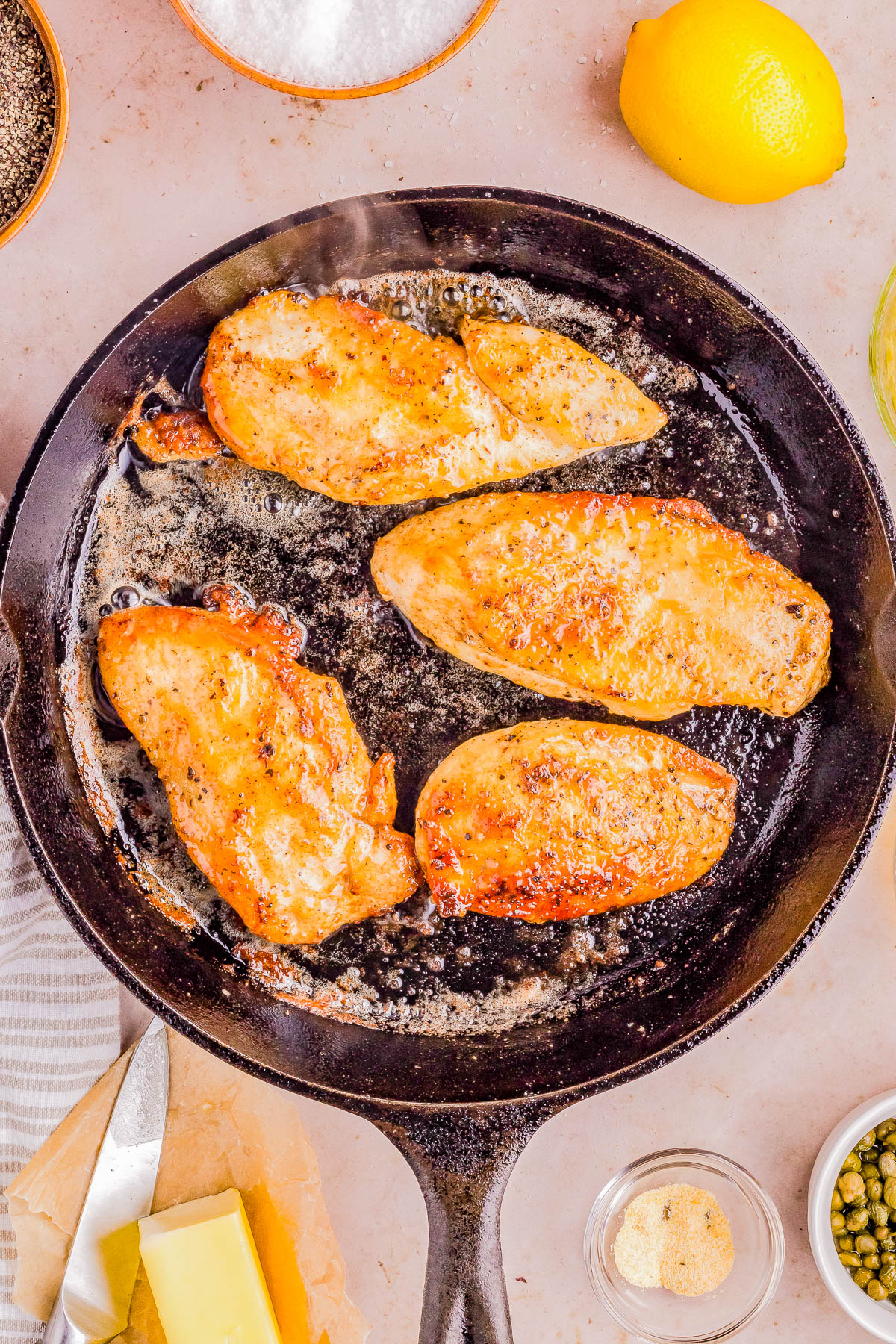 Chicken breasts being cooked in a cast iron skillet.