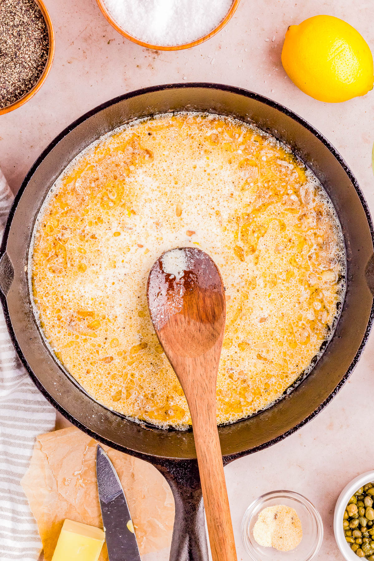Butter melting in a cast iron skillet surrounded by cooking ingredients.