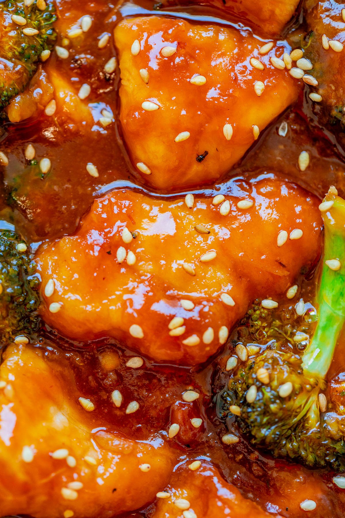 Close-up of sesame-glazed chicken with broccoli in a savory sauce.