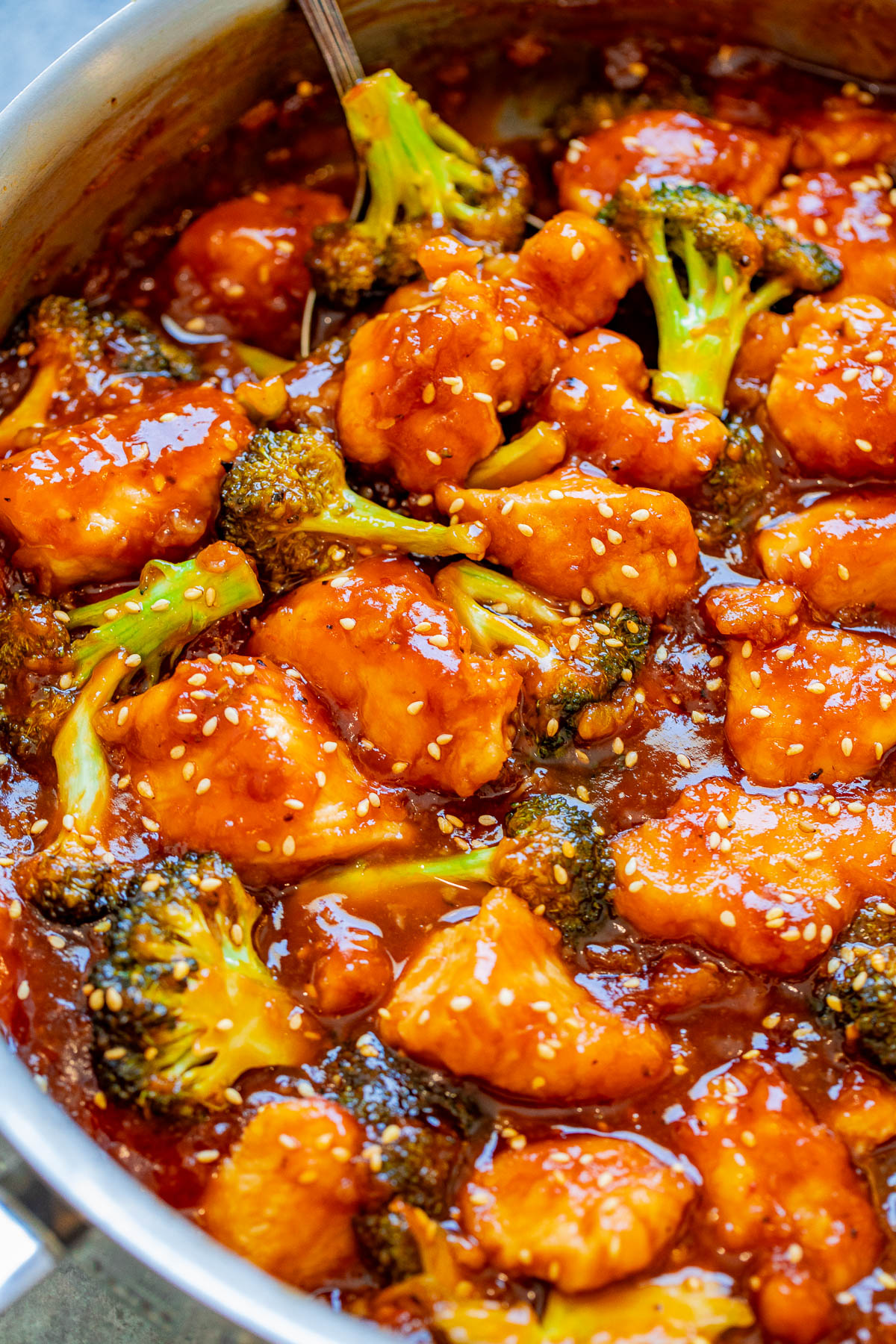 A pot of sesame sticky chicken and broccoli in a savory sauce.