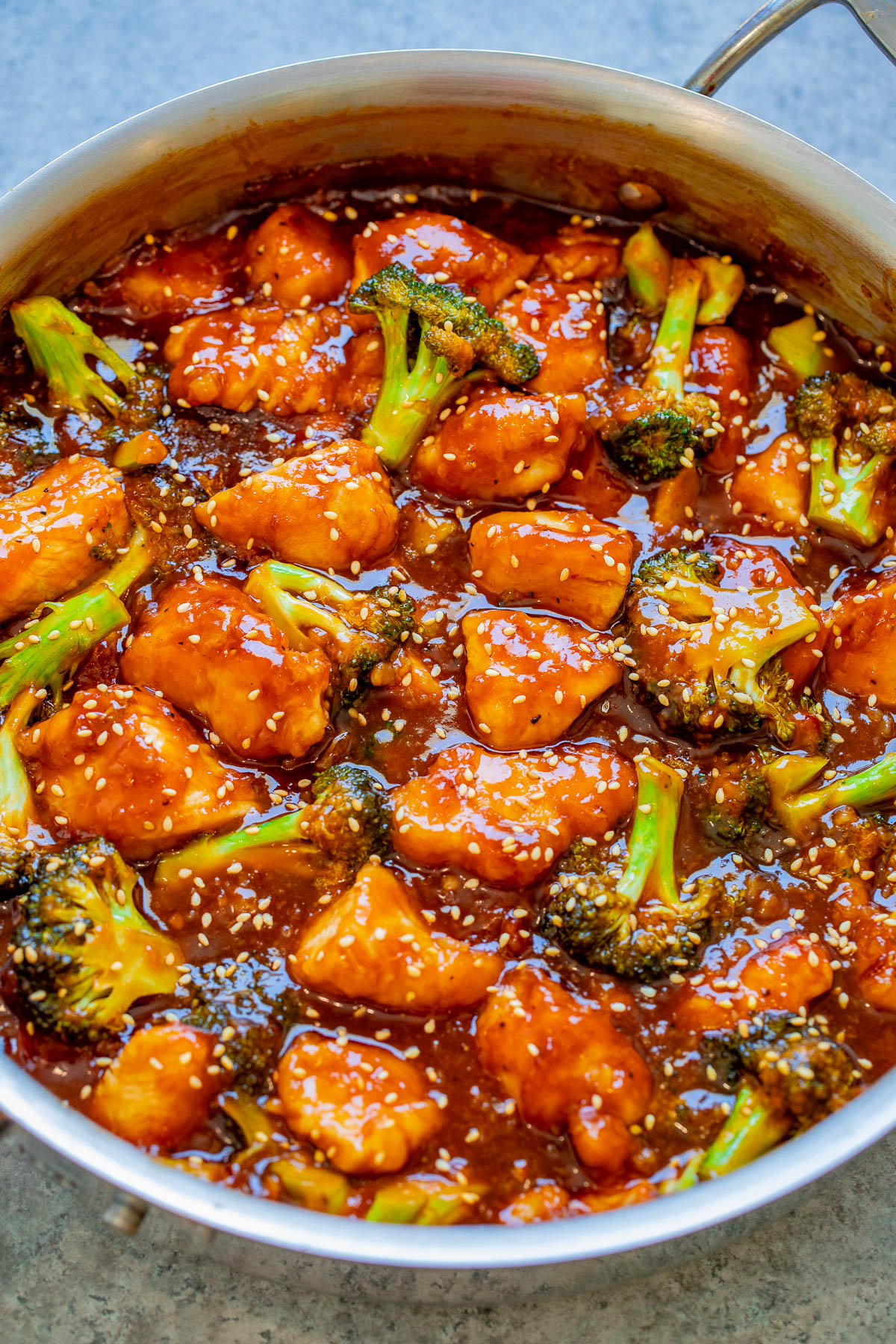 Sticky chicken and broccoli in a thick sauce, garnished with sesame seeds.