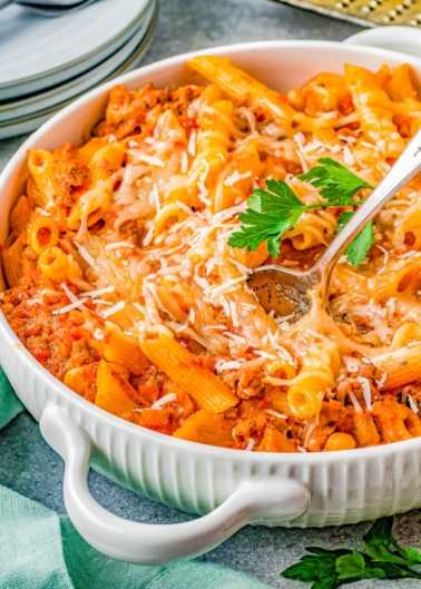 A dish of baked penne pasta with tomato sauce and melted cheese, garnished with parsley.