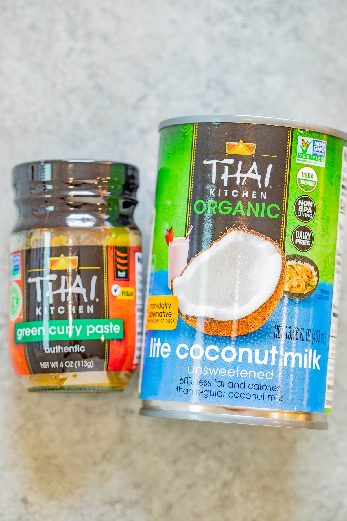 A jar of thai kitchen green curry paste next to a can of thai kitchen organic lite coconut milk.