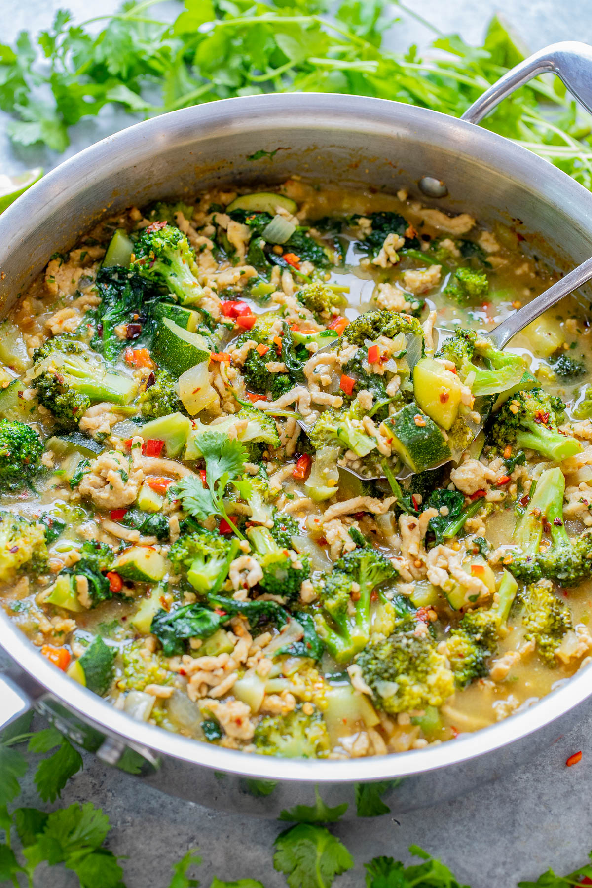 A colorful green curry with broccoli, peppers, and zucchini in a sauce, garnished with fresh cilantro.
