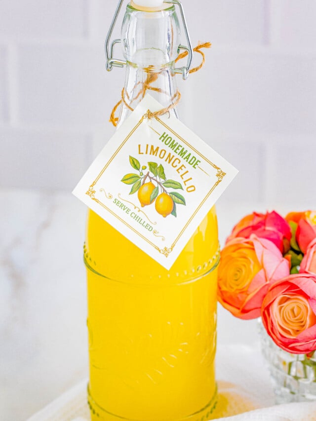 A bottle of homemade limoncello with a descriptive tag, next to a bouquet of roses.