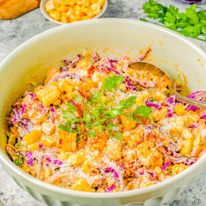 A vibrant bowl of corn salad mixed with shredded purple cabbage, topped with fresh herbs and sesame seeds.