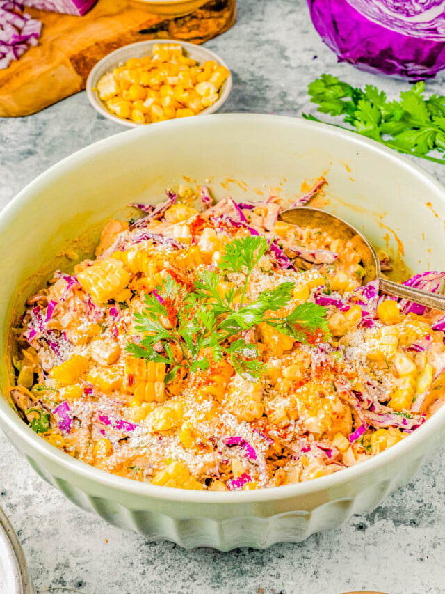 A vibrant bowl of corn salad mixed with shredded purple cabbage, topped with fresh herbs and sesame seeds.