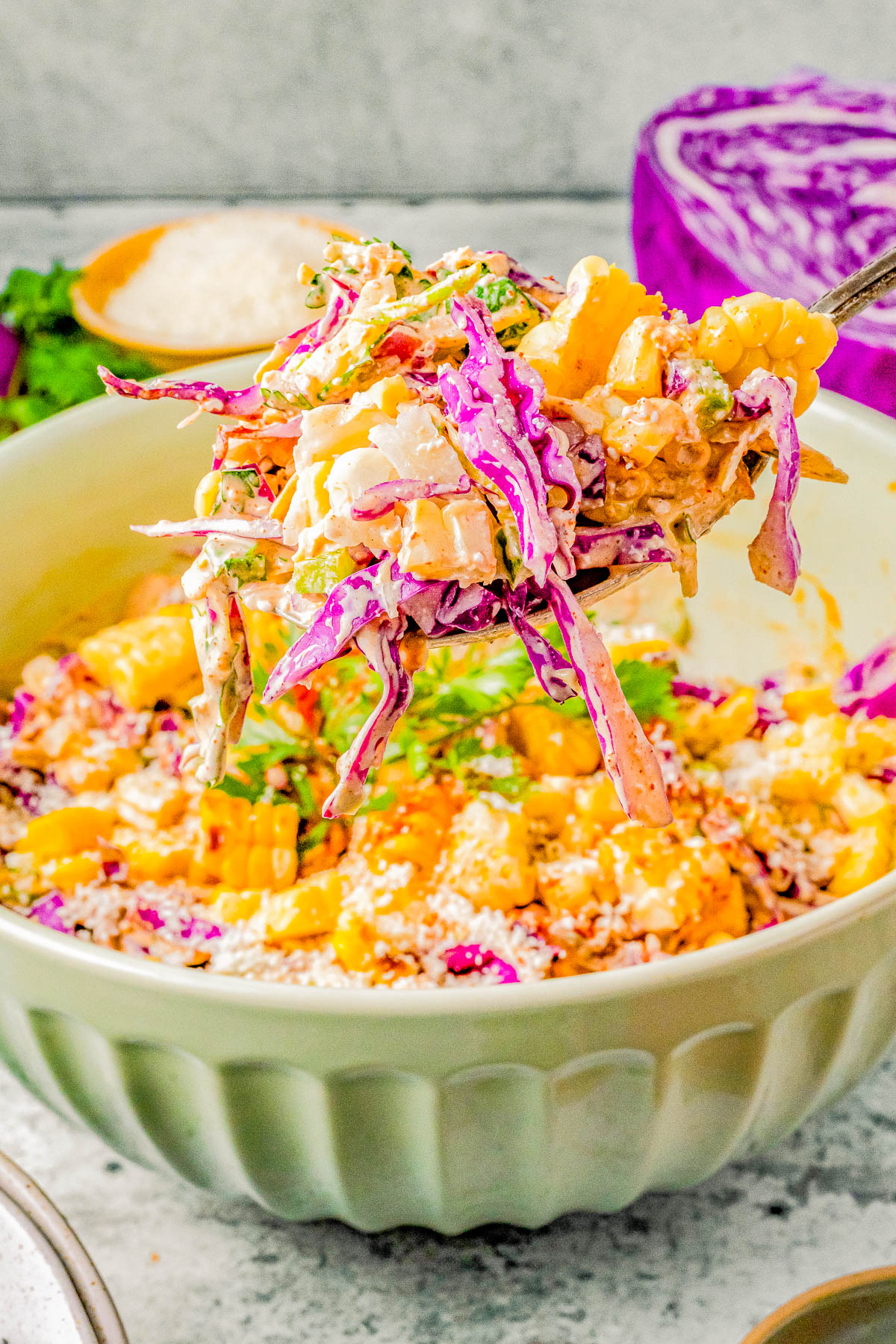 A bowl of colorful coleslaw with shredded purple cabbage, carrots, and a creamy dressing, served on a rustic table.