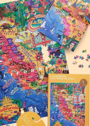 An assortment of colorful jigsaw puzzles featuring map-themed illustrations of california displayed partially completed and in their boxes.