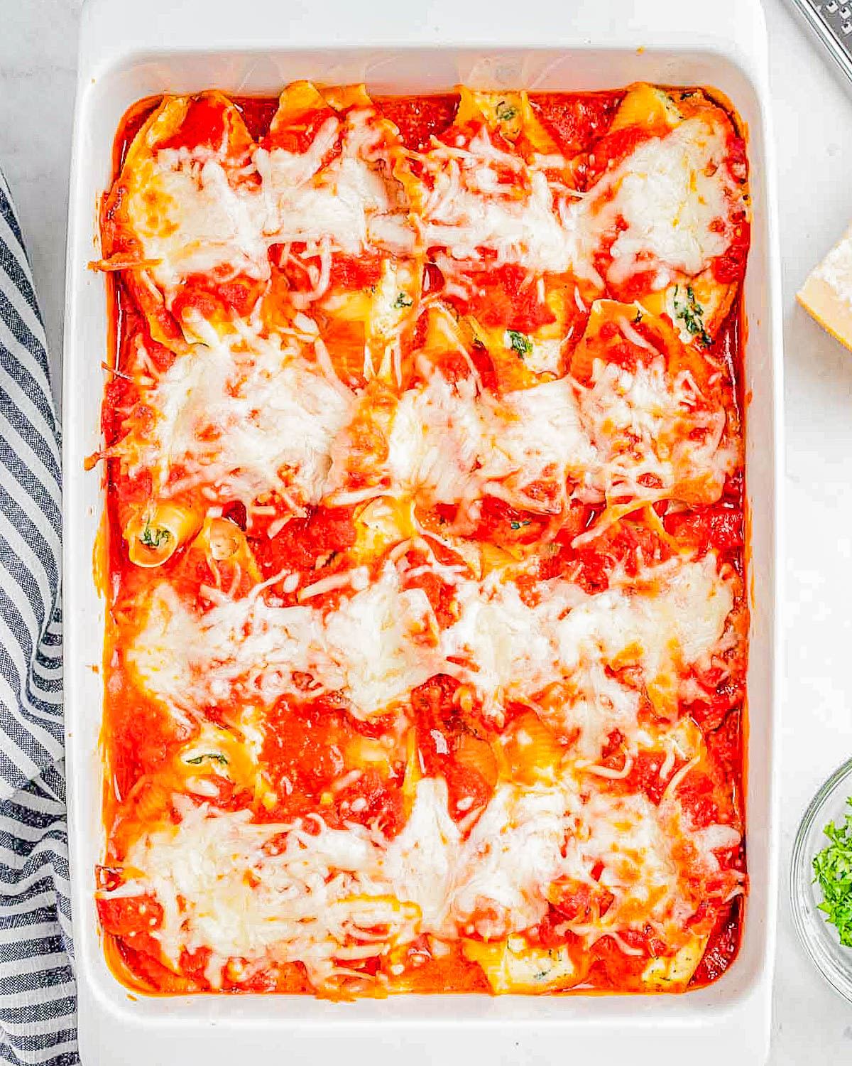 A baking dish containing freshly baked stuffed shells with melted cheese and tomato sauce.