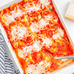 A baking dish with freshly baked stuffed shells topped with melted cheese and herbs.