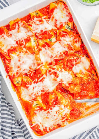 A baking dish with freshly baked stuffed shells topped with melted cheese and herbs.