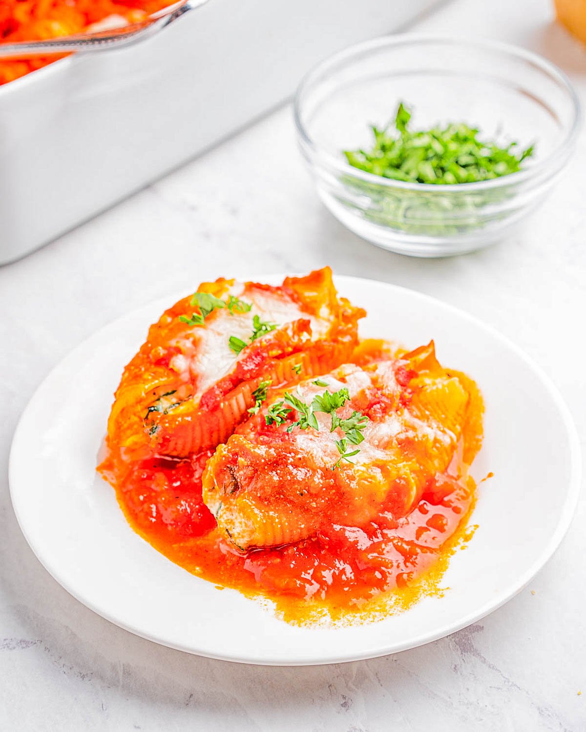A plate of stuffed shells garnished with herbs in a tomato sauce.