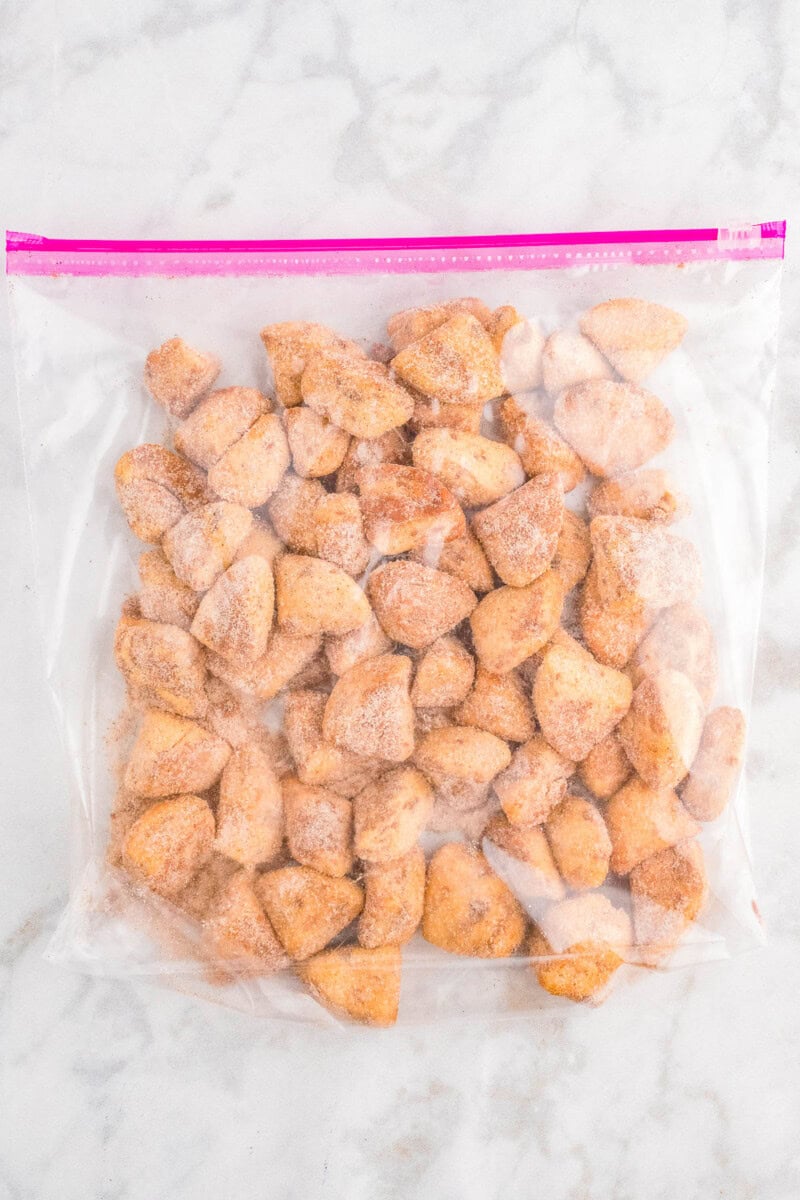 A plastic bag filled with cinnamon sugar-coated dough on a marble surface.
