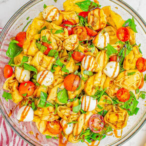 Tortellini Caprese Pasta Salad in a bowl topped with balsamic glaze.