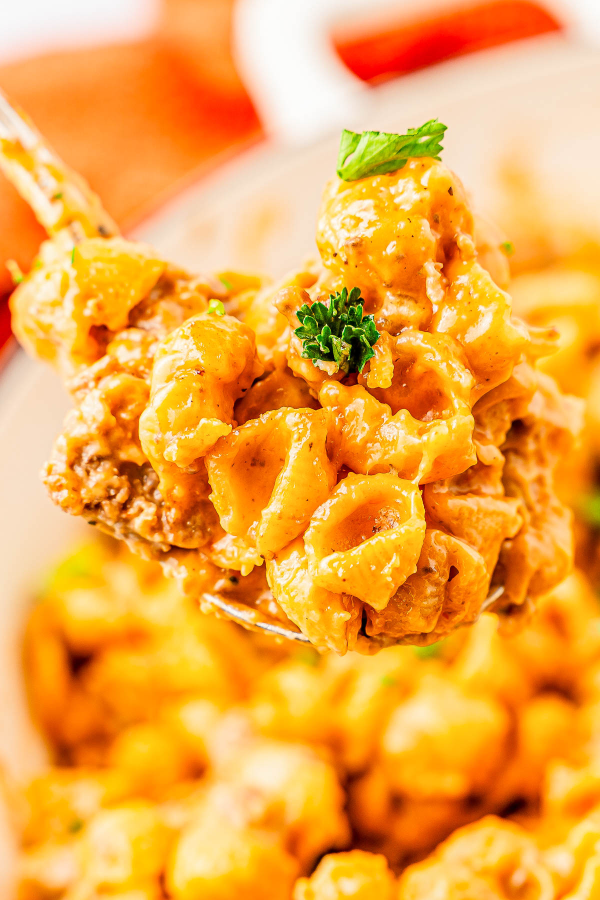 Close-up of a spoonful of creamy, cheesy pasta topped with parsley.