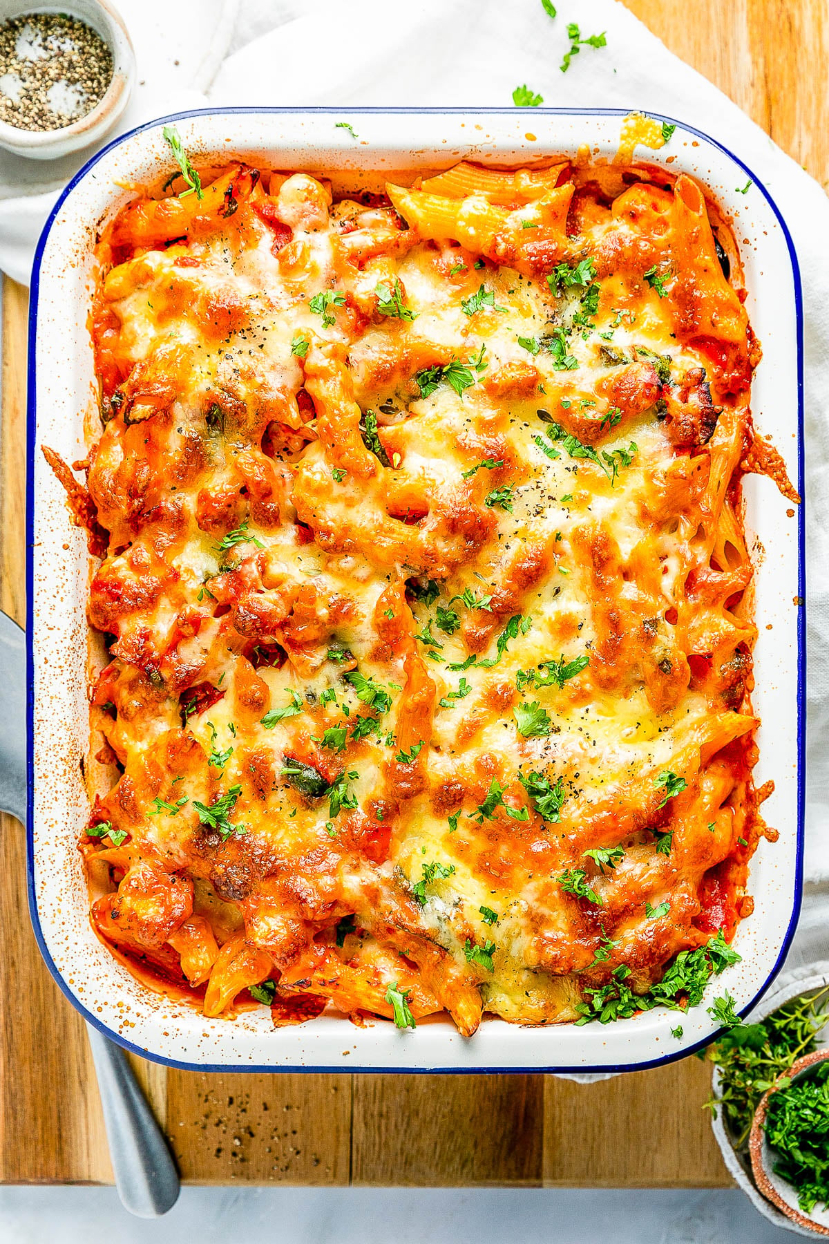 A baked pasta dish topped with melted cheese and garnished with fresh parsley in a rectangular dish.